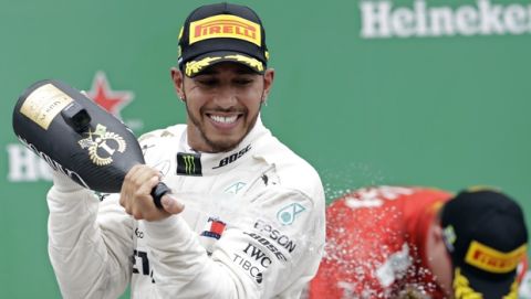 Mercedes driver Lewis Hamilton, of Britain, sprays champagne at the podium after winning the Brazilian Formula One Grand Prix at the Interlagos race track in Sao Paulo, Brazil, Sunday, Nov. 11, 2018. (AP Photo/Andre Penner)