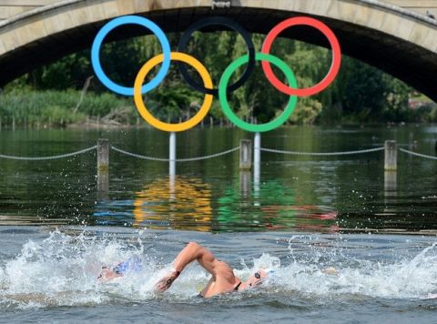 epa03354746 Swimmers pass the bridge with the Olympic rings underneath during the men's 10 km Marathon Open Water Swimming event at Hyde Park's Serpentine Lake during the London 2012 Olympic Games in London, Britain, 10 August 2012.  EPA/NEIL MUNNS