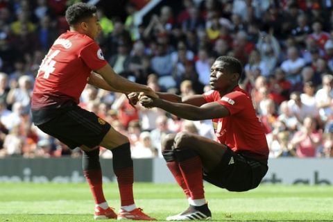 Manchester United's Jesse Lingard, left, helps Manchester United's Paul Pogba back to his feet during the English Premier League soccer match between Manchester United and Cardiff City at Old Trafford in Manchester, England, Sunday, May 12, 2019. (AP Photo/Rui Vieira)
