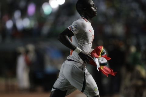 Senegal's Sadio Mane carries a Senegalese flag as he runs to throw it to supporters while celebrating Senegal's victory over Liberia during their World Cup Qualifier match at Leopold Sedar Senghor Stadium in Dakar, Senegal. Senegal came from behind to defeat Liberia 3-1. Mane scored the final goal for the home side.(AP Photo/Rebecca Blackwell)