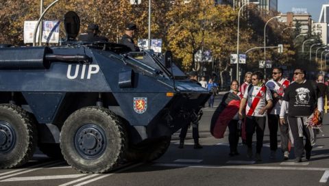 River Plate supporters walk past an Armored Personnel Carrier ahead of the Copa Libertadores Final between River Plate and Boca Juniors in Madrid, Sunday, Dec. 9, 2018. Tens of thousands of Boca and River fans are in the city for the "superclasico" at Santiago Bernabeu Stadium on Sunday. (AP Photo/Olmo Calvo)