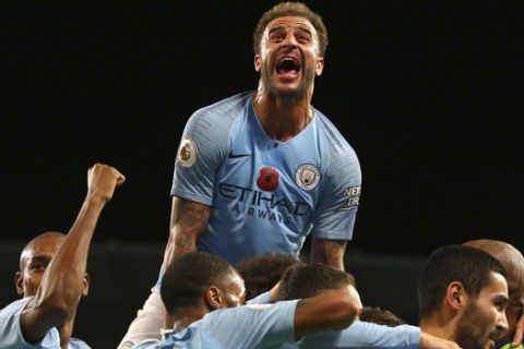 Manchester City's Kyle Walker, top, celebrates after Manchester City's Ilkay Gundogan scored his side's third goal from the penalty spot during the English Premier League soccer match between Manchester City and Manchester United at the Etihad stadium in Manchester, England, Sunday, Nov. 11, 2018. (AP Photo/Dave Thompson)