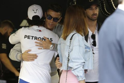 Mercedes driver Lewis Hamilton of Britain, left, welcomes Cristiano Ronaldo at the pit line ahead of the second practice session at the Monaco racetrack, in Monaco, Thursday, May 23, 2019. The Formula one race will be held on Sunday. (AP Photo/Luca Bruno)