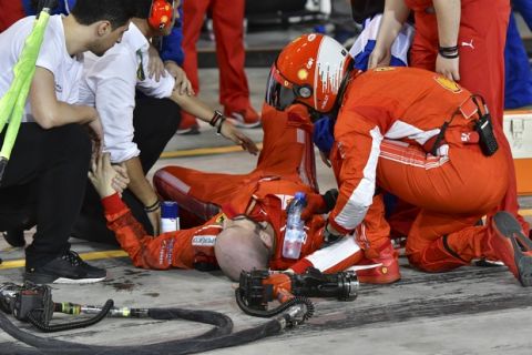 Ferrari mechanic Francesco, lies on the ground after being bitted by Ferrari driver Kimi Raikkonen during a pit stop the Bahrain Formula One Grand Prix, at the Formula One Bahrain International Circuit in Sakhir, Bahrain, Sunday, April 8, 2018. (Pool/Giuseppe Cacace Via AP)