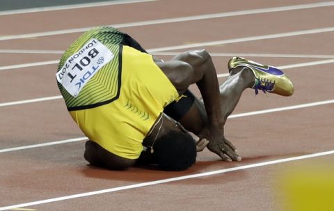 Jamaica's Usain Bolt falls on the track after suffering an injury in the men's 4x100-meter final during the World Athletics Championships in London Saturday, Aug. 12, 2017. (AP Photo/Matthias Schrader)