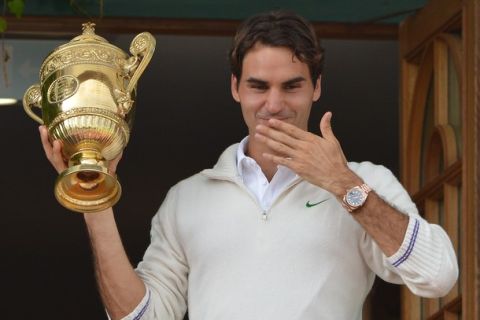 Switzerland's Roger Federer blows kisses as he celebrates with the trophy on the clubhouse balcony after his men's singles final victory over Britain's Andy Murray on day 13 of the 2012 Wimbledon Championships tennis tournament at the All England Tennis Club in Wimbledon, southwest London, on July 8, 2012. Federer won the match 4-6, 7-5, 6-3, 6-4. AFP PHOTO/ MIGUEL MEDINA   RESTRICTED TO EDITORIAL USE        (Photo credit should read MIGUEL MEDINA/AFP/GettyImages)