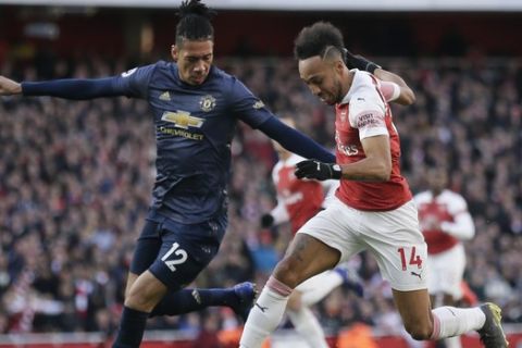 Manchester United's Chris Smalling, left, and Arsenal's Pierre-Emerick Aubameyang challenge for the ball during the English Premier League soccer match between Arsenal and Manchester United at the Emirates Stadium in London, Sunday, March 10, 2019. (AP Photo/Tim Ireland)