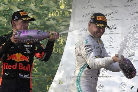 Mercedes driver Valtteri Bottas of Finland, right, is sprayed with champagne by Red Bull driver Max Verstappen of the Netherlands as they celebrate after the Australian Formula 1 Grand Prix in Melbourne, Australia, Sunday, March 17, 2019. Bottas won ahead of teammate Lewis Hamilton of Britain while Verstappen placed third. (AP Photo/Rick Rycroft)