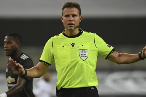 Refere Felix Brych waves away an appeal for a penalty after a check is made via VAR, on a possible hand ball in the penalty area by Manchester United's Bruno Fernandes, no penalty was given, during the Europa League semifinal soccer match between Sevilla and Manchester United in Cologne, Germany, Sunday, Aug. 16, 2020. (Ina Fassbender/Pool Via AP)