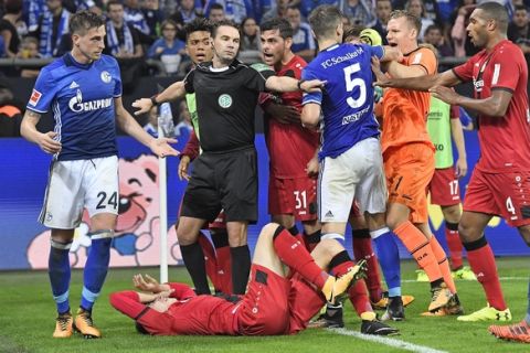 Referee Guido Winkmann trying to calm down the players after a foul during the German Bundesliga soccer match between FC Schalke 04 and Bayer Leverkusen at the Arena in Gelsenkirchen, Germany, Friday, Sept. 29, 2017. (AP Photo/Martin Meissner)