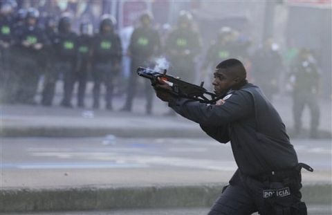 A police officer aims his weapon during clashes with Anti-World Cup demonstrators near Maracana stadium where the final World Cup game is taking place in Rio de Janeiro, Brazil, Sunday, July 13, 2014. For the final match between Argentina and Germany, authorities deployed the largest security detail in Brazil's history. (AP Photo/Leo Correa)