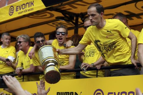 Coach Thomas Tuchel, right, receives a replica of the trophy from a fan as the truck with Borussia Dortmund players arrives at the Borsigplatz place in Dortmund, Germany, Sunday, May28, 2017. Borussia Dortmund won the German soccer cup on Saturday against Eintracht Frankfurt in Berlin. (Friso Gentsch/dpa via AP)