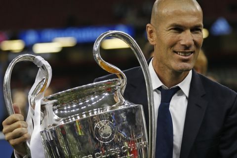 Real Madrid's head coach Zinedine Zidane celebrates with the trophy at the end of the Champions League soccer final between Juventus and Real Madrid at the Millennium Stadium in Cardiff, Wales, Saturday, June 3, 2017. Real won the match 4-1. (AP Photo/Frank Augstein)