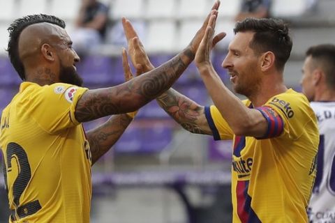 Barcelona's Arturo Vidal, left, celebrates with his teammate Lionel Messi after scoring his side's first goal during the Spanish La Liga soccer match between Valladolid and FC Barcelona at the Jose Zorrilla stadium in Valladolid, Spain, Saturday, July 11, 2020. (AP Photo/Manu Fernandez)