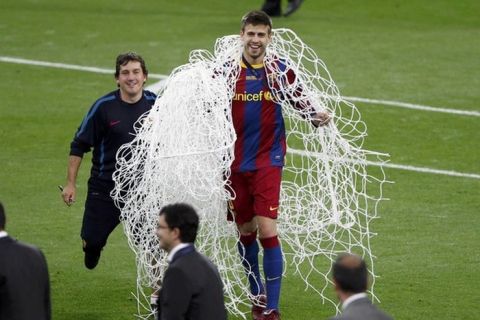 Barcelona's Gerard Pique holds the net from the goal as he celebrates after their Champions League final soccer match against Manchester United at Wembley Stadium in London May 28, 2011. REUTERS/Paul Hanna (BRITAIN  - Tags: SPORT SOCCER)  
