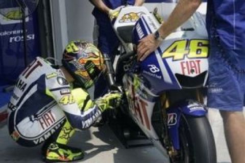 Italian MotoGP rider Valentino Rossi crouches next to his Yamaha in the pit area during the first free practice session for the Malaysian Grand Prix motorcycle racing at Sepang International Circuit in Sepang, Malaysia, Friday, Oct. 23, 2009. (AP Photo/Vincent Thian)