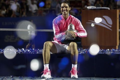 Spain's Rafael Nadal sits on the podium while holding his trophy, after defeating Taylor Fritz, of the United States, 6-3, 6-2 in the men's final of the Mexican Open tennis tournament in Acapulco, Mexico, Saturday, Feb. 29, 2020. (AP Photo/Rebecca Blackwell)