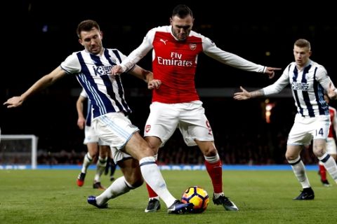 Arsenal's Lucas Perez, centre, vies for the ball with West Brom's Gareth McAuley during the English Premier League soccer match between Arsenal and West Bromwich Albion at Emirates stadium in London, Monday, Dec. 26, 2016. (AP Photo/Kirsty Wigglesworth)