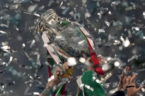 Italy's team celebrates with the trophy after winning the Euro 2020 soccer championship final between England and Italy at Wembley stadium in London, Sunday, July 11, 2021. UEFA has decided the future of soccers European Championship for the next decade. The United Kingdom and Ireland will host in 2028 and an unusual Italy-Turkey co-hosting plan was picked for 2032. (AP Photo/Frank Augstein, Pool, File)