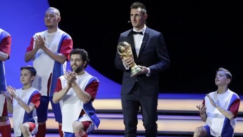 Former German soccer international and trophy bearer Miroslav Klose holds the World Cup trophy during the 2018 soccer World Cup draw in the Kremlin in Moscow, Friday, Dec. 1, 2017. (AP Photo/Dmitri Lovetsky)