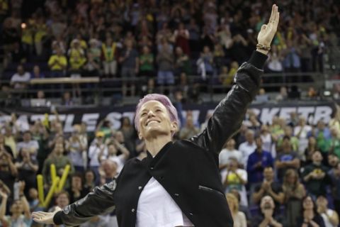 Megan Rapinoe, of the U.S. women's World Cup championship soccer team, motions to fans while being introduced during the first half of a WNBA basketball game between the Seattle Storm and the Dallas Wings Friday, July12, 2019, in Seattle. Rapinoe returns to National Women's Soccer League play with her team, Reign FC, on July 28 for a match in Tacoma, Wash. (AP Photo/Elaine Thompson)