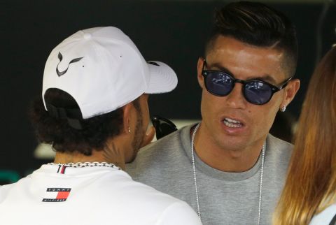 Cristiano Ronaldo, right, talks with Mercedes driver Lewis Hamilton of Britain at the pit line ahead of the second practice session at the Monaco racetrack, in Monaco, Thursday, May 23, 2019. The Formula one race will be held on Sunday. (AP Photo/Luca Bruno)