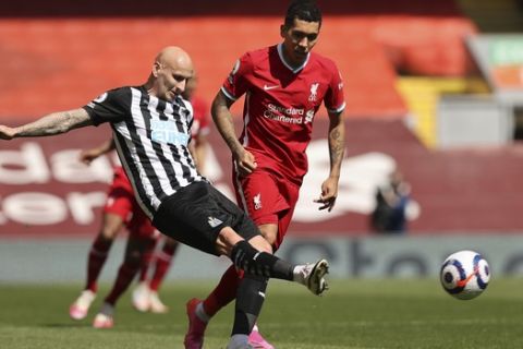 Newcastle's Jonjo Shelvey, ,left, challenges for the ball with Liverpool's Roberto Firmino during the English Premier League soccer match between Liverpool and Newcastle United at Anfield stadium in Liverpool, England, Saturday, April 24, 2021. (Clive Brunskill, Pool via AP)
