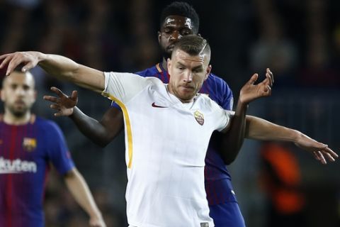 Roma's Edin Dzeko, front , challenges for the ball with Barcelona's Samuel Umtiti during a Champions League quarter-final, first leg soccer match between FC Barcelona and Roma at the Camp Nou stadium in Barcelona, Spain, Wednesday, April 4, 2018.(AP Photo/ Manu Fernandez)