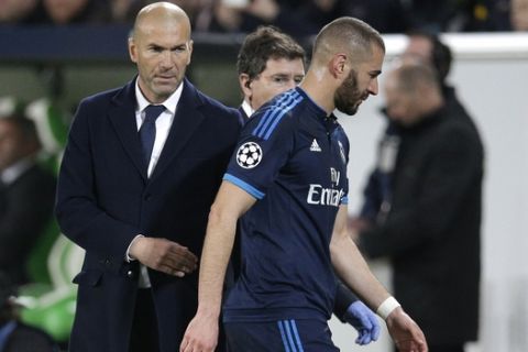 Real Madrid's head coach Zinedine Zidane, left, looks on as Real Madrid's Karim Benzema leaves the pitch after suffering an injury during the Champions League first leg quarterfinal soccer match between VfL Wolfsburg and Real Madrid in Wolfsburg, Germany, Wednesday, April 6, 2016. (AP Photo/Michael Sohn)