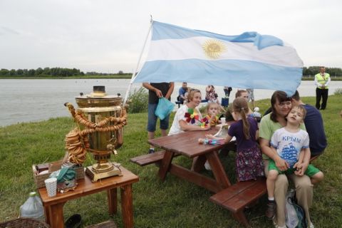 People sit by a tea samovar during a celebration to mark Lionel Messi's birthday near Argentina's training camp base at the 2018 World Cup in Bronnitsy, Russia, Sunday, June 24, 2018. Wth a cake sculpture and a music festival the town of Bronnitsy celebrated the striker's 31st birthday. (AP Photo/Ricardo Mazalan)
