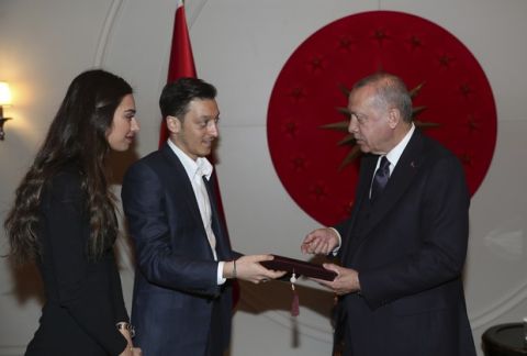 In this photo dated Friday, March 15, 2019, made available Sunday March 17, 2019, Turkey's President Recep Tayyip Erdogan, receives an invitation card for their wedding from Turkish-German soccer star Mesut Ozil and his fiancee Amine Gulse in Istanbul. (Presidential Press Service via AP, Pool)
