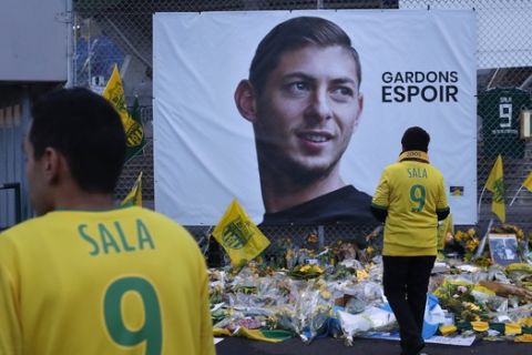 Nantes soccer team supporters stand by a poster of Argentinian player Emiliano Sala and reading "Let's keep hope" outside La Beaujoire stadium before the French soccer League One match Nantes against Saint-Etienne, in Nantes, western France, Wednesday, Jan.30, 2019. Sala disappeared over the English Channel on Jan. 21, 2019 as it flew from France to Wales. Sala had just been signed by Premier League club Cardiff. (AP Photo/Thibault Camus)