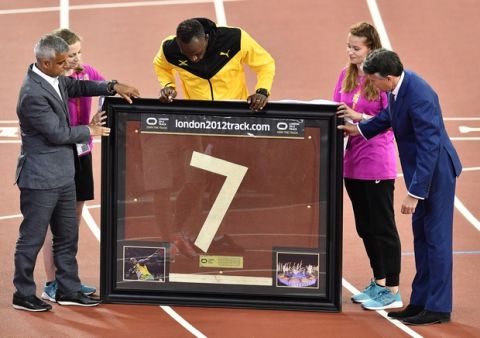 Jamaica's Usain Bolt looks at a piece of the track presented to him to mark his athletics career during the World Athletics Championships in London Sunday, Aug. 13, 2017.(AP Photo/Martin Meissner)