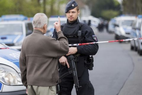 A man talks to a police officer who secures the scene where the team bus of Borussia Dortmund was damaged in an explosion the evening before in Dortmund, western Germany, Wednesday morning April 12, 2017. One player and one police officer were injured in the blast. (Rolf Vennenbernd/dpa via AP)