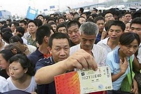 A man displays a ticket to next month's Olympic Games while waiting in a crowd to buy more, outside a ticket office in Beijing early Friday July 25, 2008. Thousands waited overnight for a chance to buy tickets from the last batch of Olympic tickets which went on sale Friday morning. (AP Photo/Greg Baker)