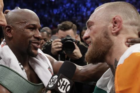 Floyd Mayweather Jr., left, speaks with Conor McGregor after a super welterweight boxing match Saturday, Aug. 26, 2017, in Las Vegas. (AP Photo/Isaac Brekken)