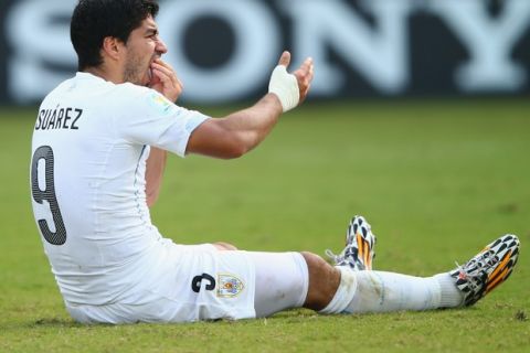 NATAL, BRAZIL - JUNE 24:  Luis Suarez of Uruguay reacts after a clash during the 2014 FIFA World Cup Brazil Group D match between Italy and Uruguay at Estadio das Dunas on June 24, 2014 in Natal, Brazil.  (Photo by Clive Rose/Getty Images)