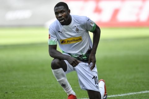 Moenchengladbach's Marcus Thuram gets up after taking the knee after scoring his side's second goal during the German Bundesliga soccer match between Borussia Moenchengladbach and Union Berlin in Moenchengladbach, Germany, Sunday, May 31, 2020. The German Bundesliga becomes the world's first major soccer league to resume after a two-month suspension because of the coronavirus pandemic. (AP Photo/Martin Meissner, Pool)