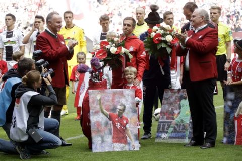 Bayern's Philipp Lahm, center, stands besides his son Julian during his farewell celebration besides Bayern president Uli Hoeness, right, and CEO Karl-Heinz Rummenigge, left, prior to the German first division Bundesliga soccer match between FC Bayern Munich and SC Freiburg at the Allianz Arena stadium in Munich, Germany, Saturday, May 20, 2017. (AP Photo/Matthias Schrader)
