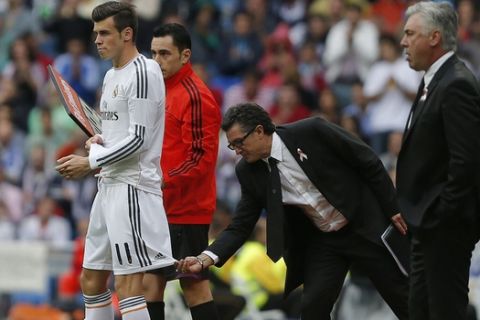 Real Madrid's representative Miguel Porlan Chendo, centre, touches Gareth Bale's uniform, left, as he wait to enter the field beside coach Carlo Ancelotti, right, during a Spanish La Liga soccer match against Malaga at the Santiago Bernabeu stadium in Madrid, Spain, Saturday, Oct. 19, 2013. (AP Photo/Andres Kudacki)