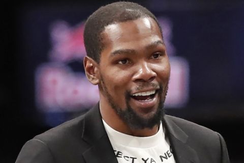 FILE - In this Dec. 26, 2019, file photo, injured Brooklyn Nets player Kevin Durant smiles as he greets teammates returning to the bench during a timeout in the second half of an NBA basketball game against the New York Knicks, in New York. Brooklyn Nets forward Kevin Durant has joined the ownership group of Major League Soccer's Philadelphia Union. Durant, a 10-time NBA All-Star, has a 5% ownership stake, with an option for 5% more in the near future, the Union announced Monday, June 15, 2020. (AP Photo/Kathy Willens, File)