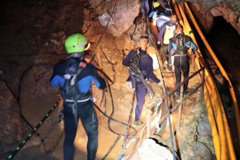 In this undated photo released by Royal Thai Navy on Saturday, July 7, 2018, Thai rescue team members walk inside a cave where 12 boys and their soccer coach have been trapped since June 23, in Mae Sai, Chiang Rai province, northern Thailand. The local governor in charge of the mission to rescue them said Saturday that cooperating weather and falling water levels over the last few days had created appropriate conditions for evacuation, but that they won't last if it rains again. (Royal Thai Navy via AP)