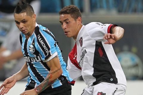 Ezequiel Ponce of Argentina's Newell's Old Boys, right, fights for the ball with Para of Brazil's Gremio during their Copa Libertadores soccer match in Porto Alegre, Brazil, Thursday, March 13, 2014. (AP Photo/Nabor Goulart)