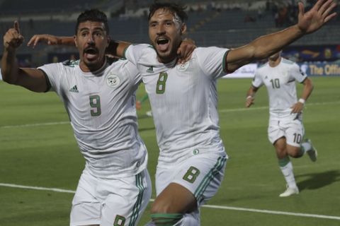 Algeria's Baghdad Bounedjah, left, and Mohamed Belaili celebrate after a goal during the African Cup of Nations round of 16 soccer match between Algeria and Guinea in 30 June stadium in Cairo, Egypt, Sunday, July 7, 2019. (AP Photo/Hassan Ammar)