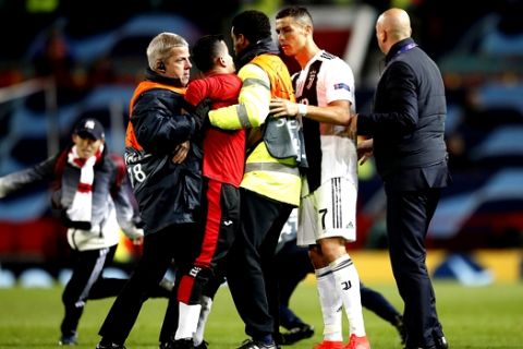 Juventus' Cristiano Ronaldo tries to calm the situation as pitch invaders are tackled by stewards after the  Champions League soccer match at Old Trafford, Manchester, England, Tuesday Oct. 23, 2018. (Martin Rickett/PA via AP)