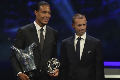 Dutch soccer player Virgil van Dijk of Liverpool, left, holds the award of men's player of the year 2018/19 as he poses with UEFA President Aleksander Ceferin during the group stage draw at the Grimaldi Forum, in Monaco, Thursday, Aug. 29, 2019. (AP Photo/Daniel Cole)