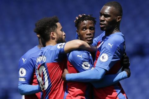 Crystal Palace's Wilfried Zaha, centre, is congratulated by teammates after scoring his team's second goal during the English Premier League soccer match between Crystal Palace and Aston Villa at Selhurst Park in London, Sunday, May 16, 2021. (AP Photo/Henry Browne/Pool)
