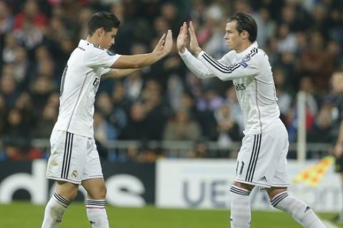 Real Madrid's James Rodriguez, left, is substituted for Real Madrid's Gareth Bale during a Group B Champions League soccer match between Real Madrid and Liverpool at the Santiago Bernabeu stadium in Madrid, Spain, Tuesday Nov. 4, 2014. (AP Photo/Paul White)