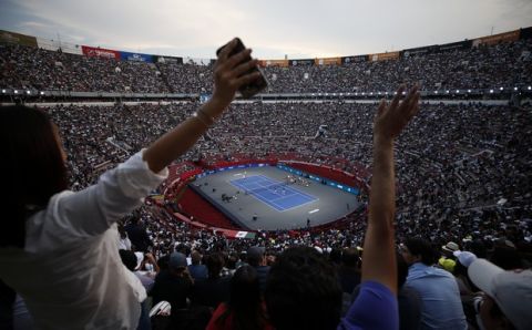 Spectators wave from the stands as brothers Bob and Mike Bryan of the U.S., left, take on Mexico's Miguel Angel Reyes Varela and Santiago Gonzalez in an exhibition doubles tennis match in the Plaza de Toros bullring in Mexico City, Saturday, Nov. 23, 2019. Roger Federer of Switzerland and Germany's Alexander Zverev were also to face off in the converted bullring Saturday, the fourth stop in a tour of Latin America by the tennis greats.(AP Photo/Rebecca Blackwell)
