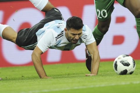 Argentina's Sergio Aguero, center, falls down as he challenges for the ball with Nigeria's Chidozie Awaziem, right, and John Obi Mikel, left, during the international friendly soccer match between Argentina and Nigeria in Krasnodar, Russia, Tuesday, Nov. 14, 2017. (AP Photo/Sergey Pivovarov)